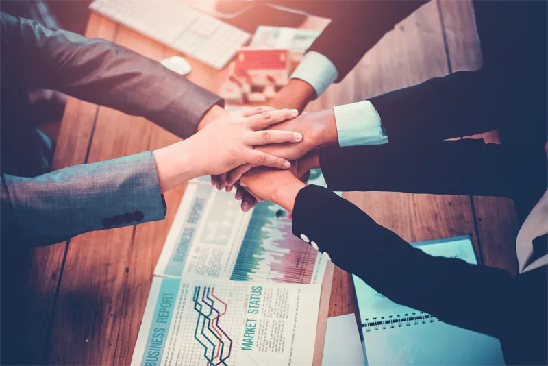 Business hands together on documents.